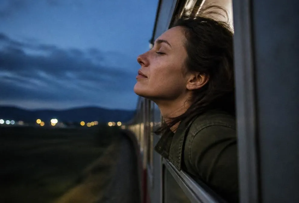 Traveler taking a deep clear breath at an open train window