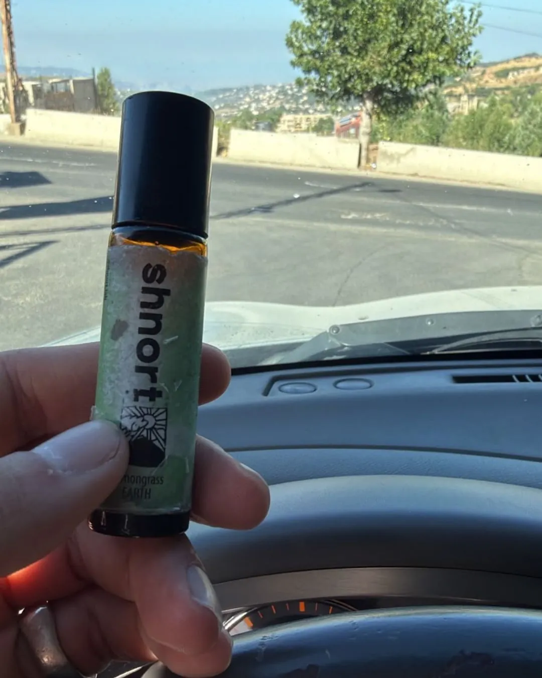 shnort Lemongrass EARTH roller held up in a car